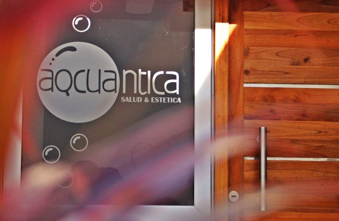 El logo de Aqcuantica grabado en el vidrio de la entrada, junto a la puerta de madera
